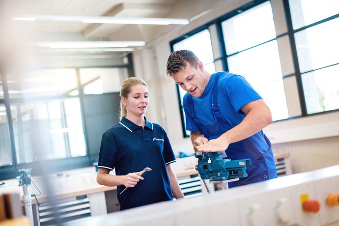 © Mainova/AndreFormer Ausbilderin prüft die Arbeit eine Auszubildenden an der Werkbank