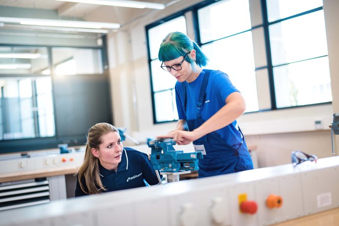 © Mainova/AndreFormer Ausbilderin kontrolliert die Arbeit einer Auszubildenden an einen Schraubstock