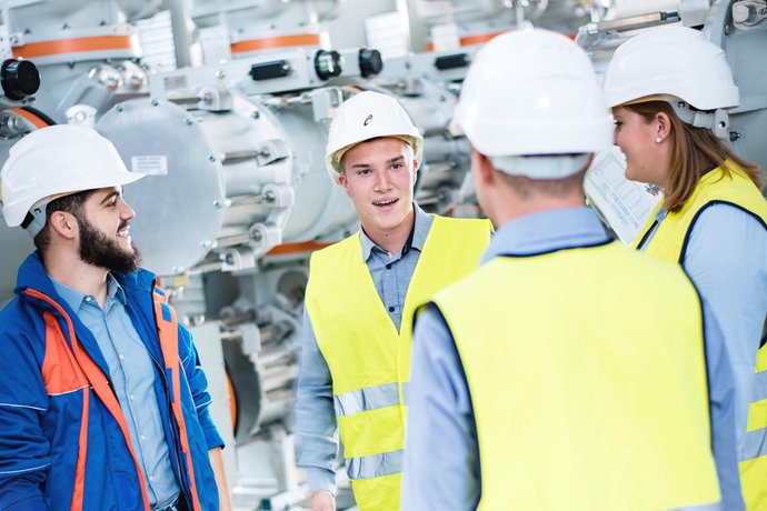 © Mainova/AndreFormer Gruppe mit Studierenden stehen vor einer Maschine und sprechen miteinander