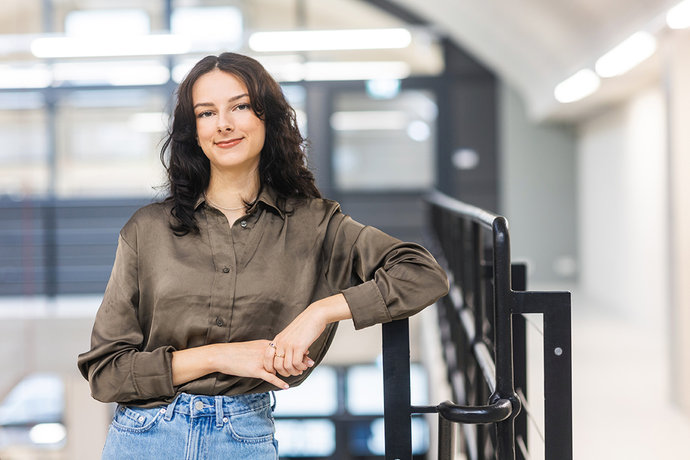 © Mainova/AndreFormer Megan Salamon steht angelehnt an einem Geländer im Ausbildungszentrum und schaut in die Kamera