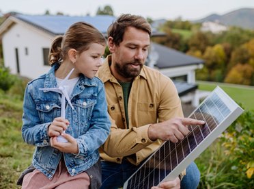 © www.istock.com/Halfpoint Vater zeigt seiner Tochter ein PV-Modul