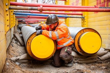 Monteur kniet zwischen 2 neuen Fernwärmerohren