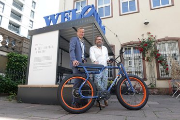 Zwei Menschen stehen hinter einem Fahrrad