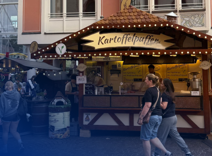 Kartoffelpuffer Stand auf dem Weihnachtsmarkt und Personen laufen davor