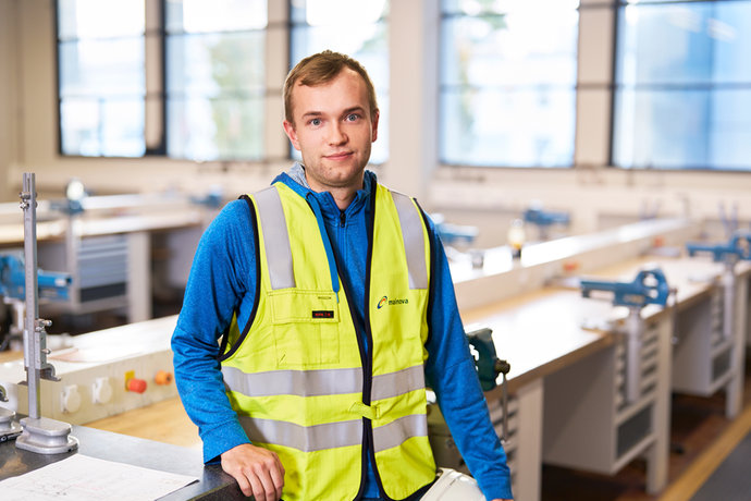 Jesco Hoppe in Warnweste und blauem Hoodie lehnt an einer Werkbank in einem Schulungsraum.