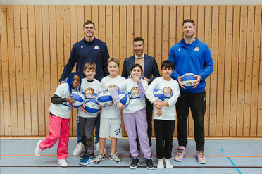 Gruppenbild eines Kinder-Basketballteams mit zwei Trainern und einem weiteren Mann