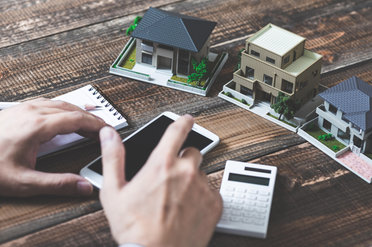 © stock.adobe.com/beeboys Modellhäuser, Smartphone und Taschenrechner