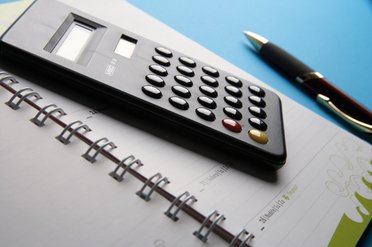 Aufgeschlagener Notizblock und Taschenrechner
