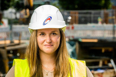 Eine Person mit Schutzhelm und Warnweste auf einer Baustelle.