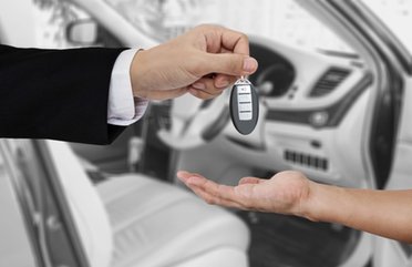 Ein Autoschlüssel wird von einer zur anderen Hand übergeben.