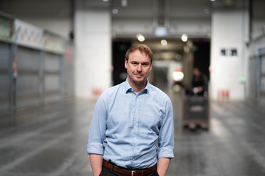 Mann mit langem blauen Hemd schaut den Betrachter an und lächelt 