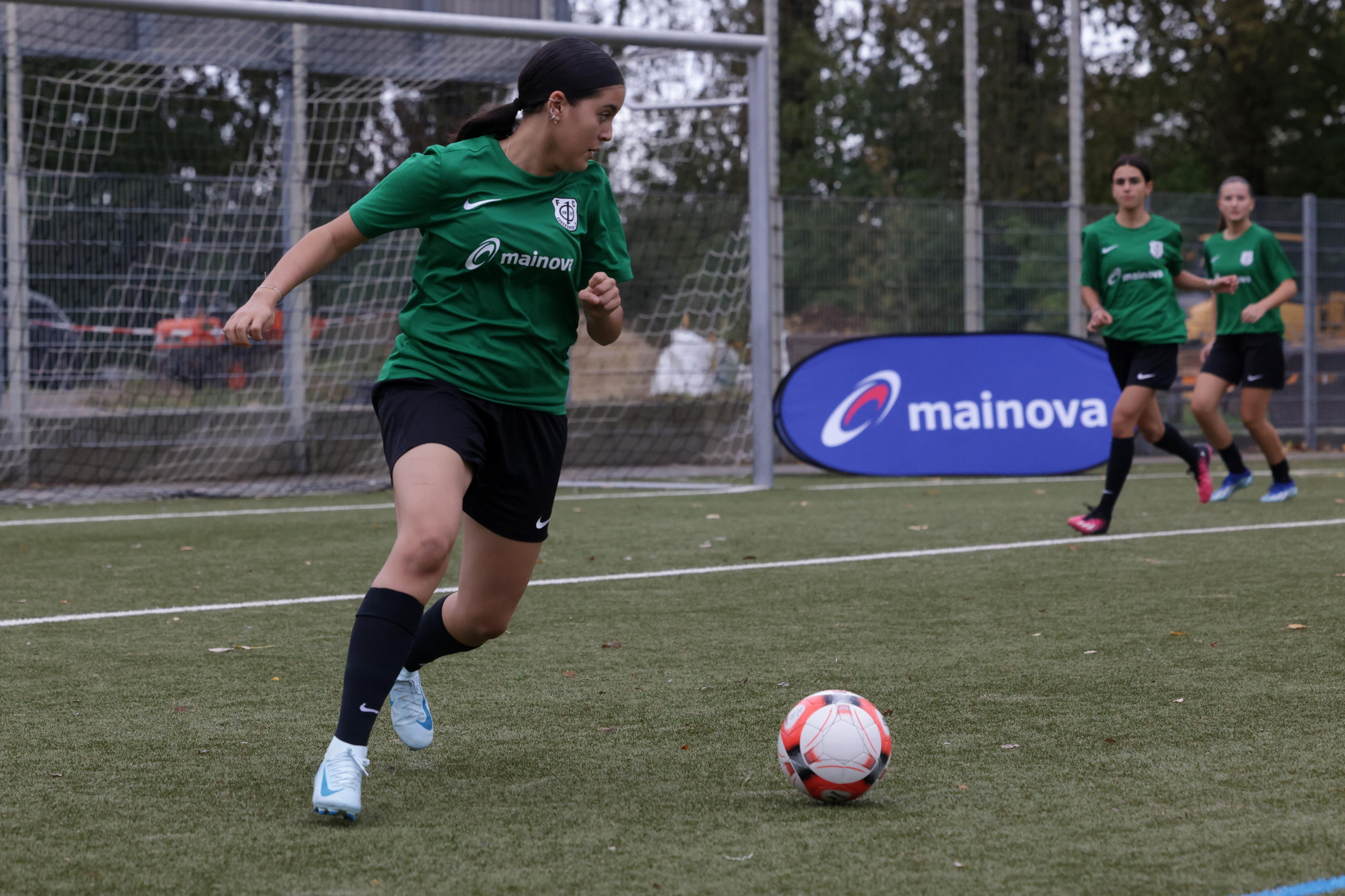 Mädchen in grünem Trikot spielt Fußball