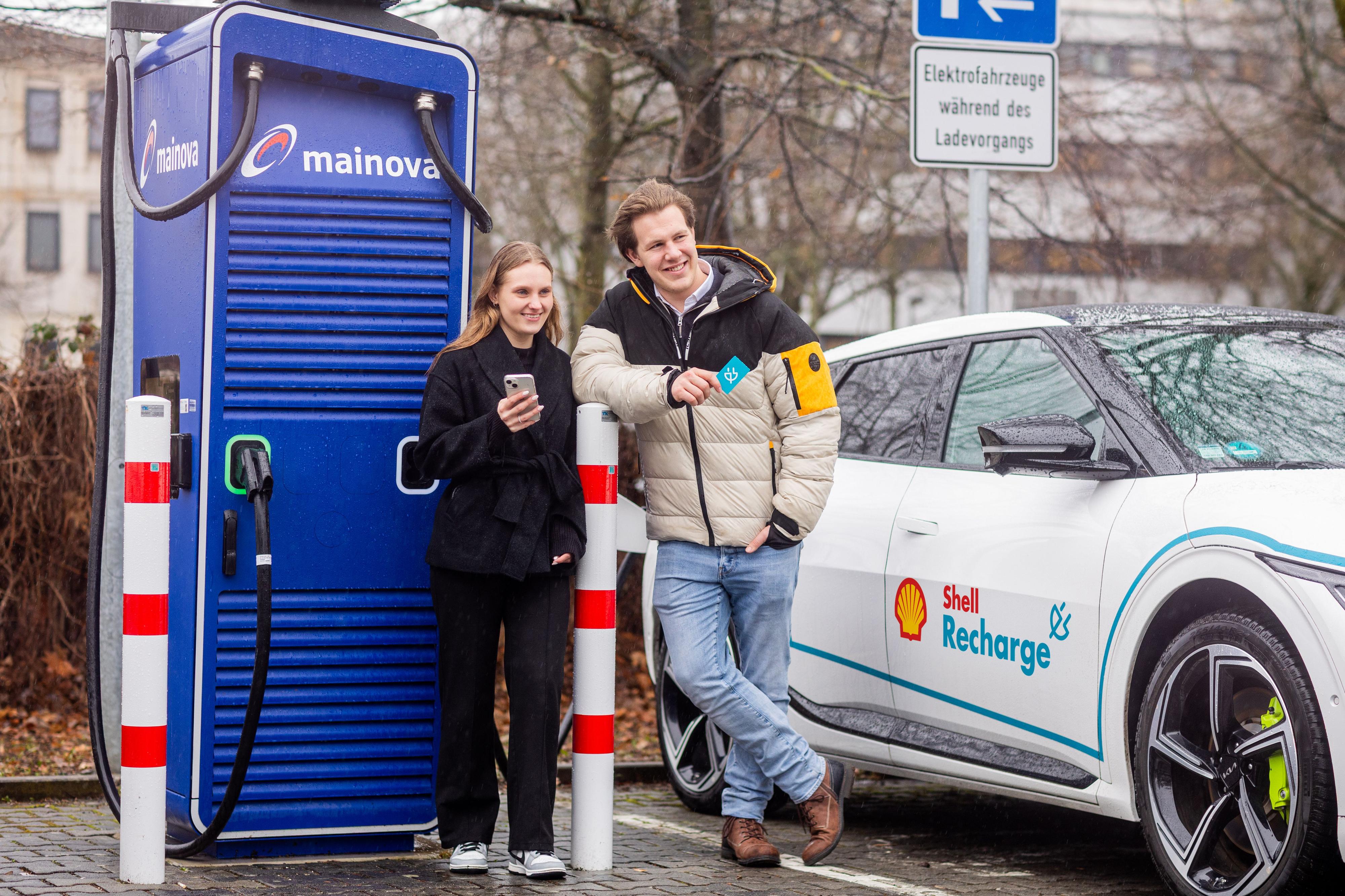 Zwei junge Menschen vor einer Stromtankstelle