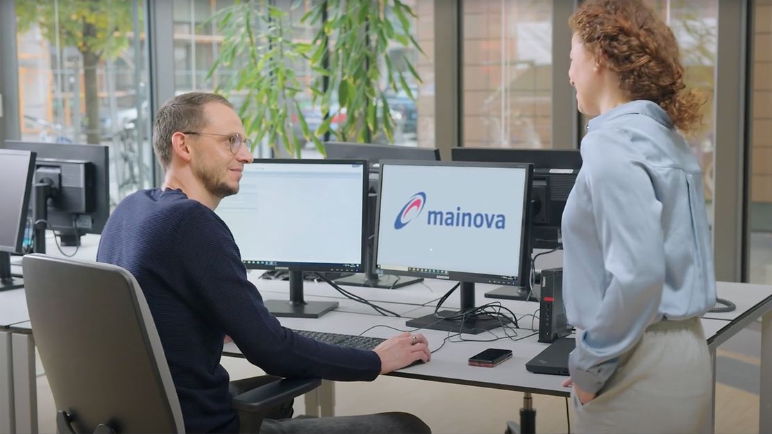© Mainova/AgenturungesHerz IT Ausbilder sitzt am Computer und neben ihm steht eine Auszubildende und fragt ihn etwas