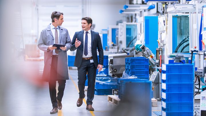 Zwei Geschäftsleute laufen durch Produktionshalle