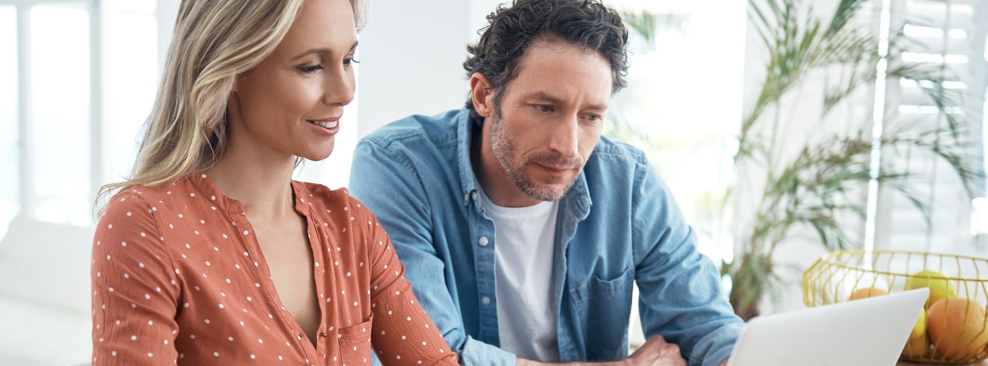© iStock.com/shapecharge Mann und Frau schauen zu Hause gemeinsam auf Laptop
