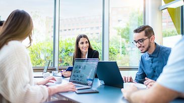 © Mainova/AndreFormer Mann sitzt am Notebook und Frau schaut lächelnd zu ihm rüber