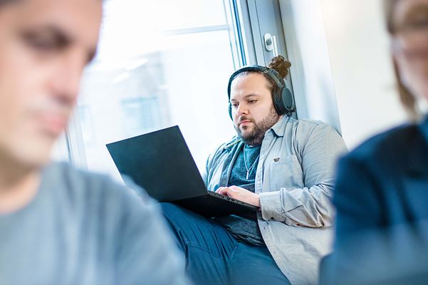 © Mainova Mann sitzt auf Fensterbank mit einen Notebook auf den Knien