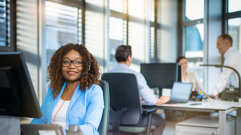 © Mainova/AndreFormer Frau sitzt am Schreibtisch vor einen Monitor und schaut in den Raum