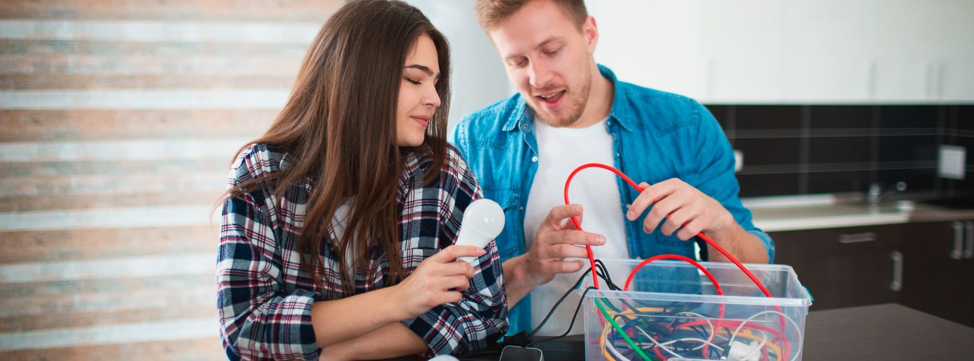 Junges Paar räumt Kabel und Elektrogeräte aus einer Kiste.