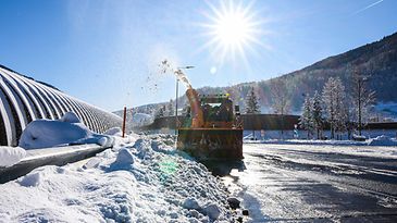 Eine verschneite Straße wird von einem Schneerpflug geräumt