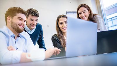 Gruppe von Studierenden schaut gemeinsam auf ein Notebook Monitor