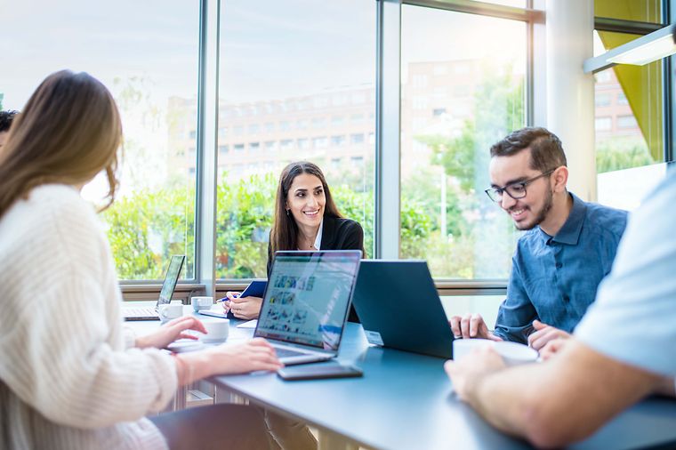 © Mainova/AndreFormer Studierende sprechen am Tisch gemeinsam während die Notebooks eingeschaltet sind