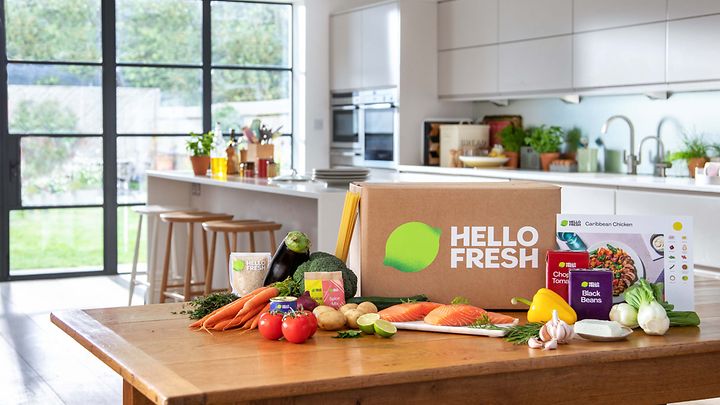 Eine Küche mit einem HelloFresh-Karton und frischen Zutaten auf einem Holztisch.