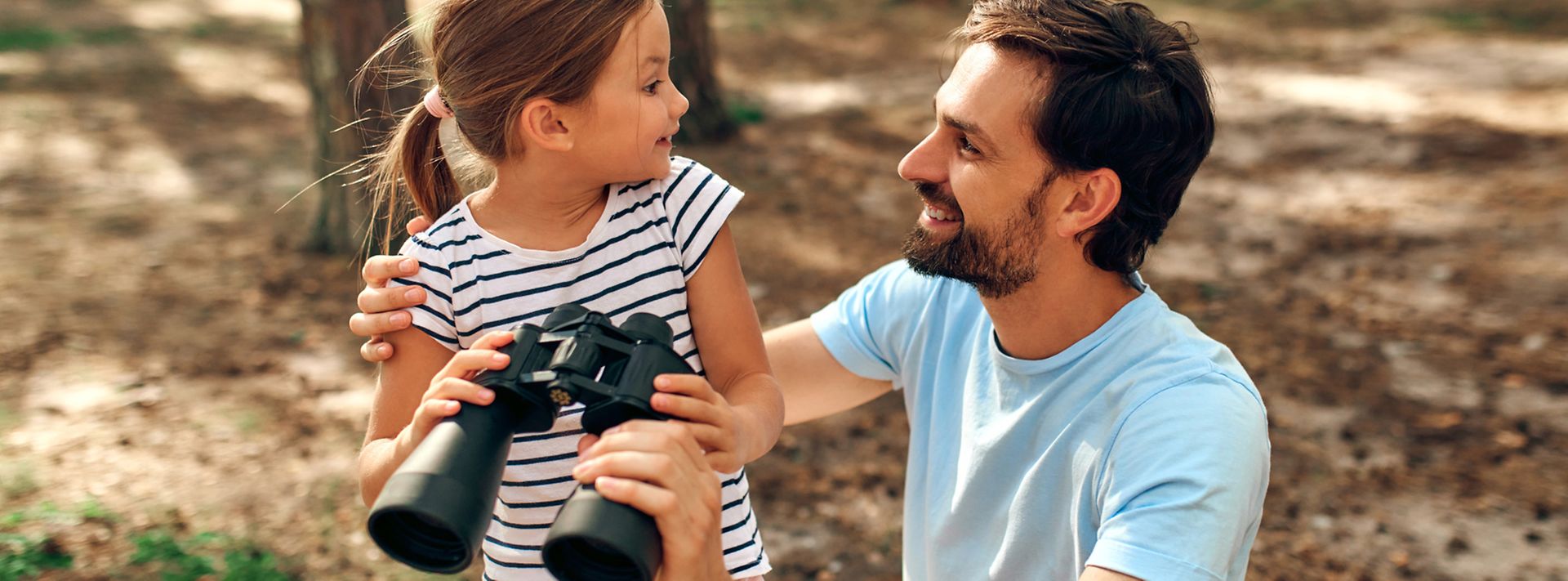 © istock.com/ValeriiApetroaiei Glücklicher Vater mit Tochter die ein Fernglas in der Hand hält