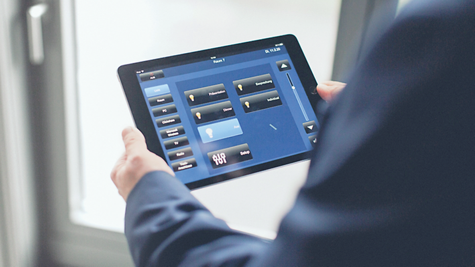 Mann hält Tablet mit App zur Lichtsteuerung