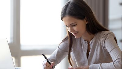 Schülerin schreibt auf einem Block ihre Bewerbung vor