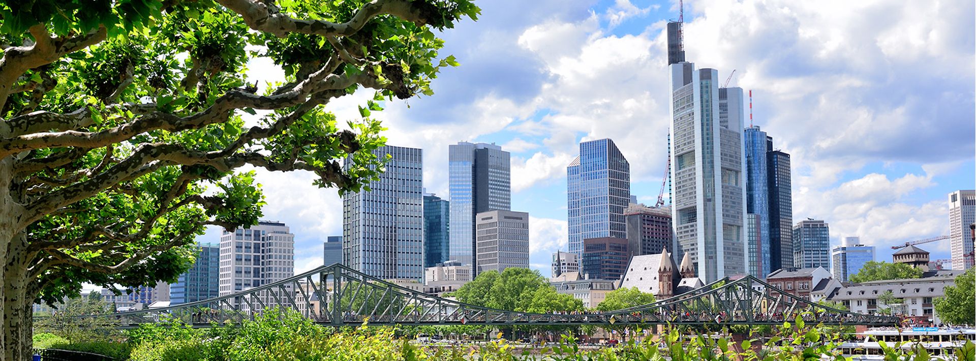 © istock.com/alxpin Blick vom Mainufer aus auf den Eisernen Steg in Frankfurt mit Skyline im Hintergrund.