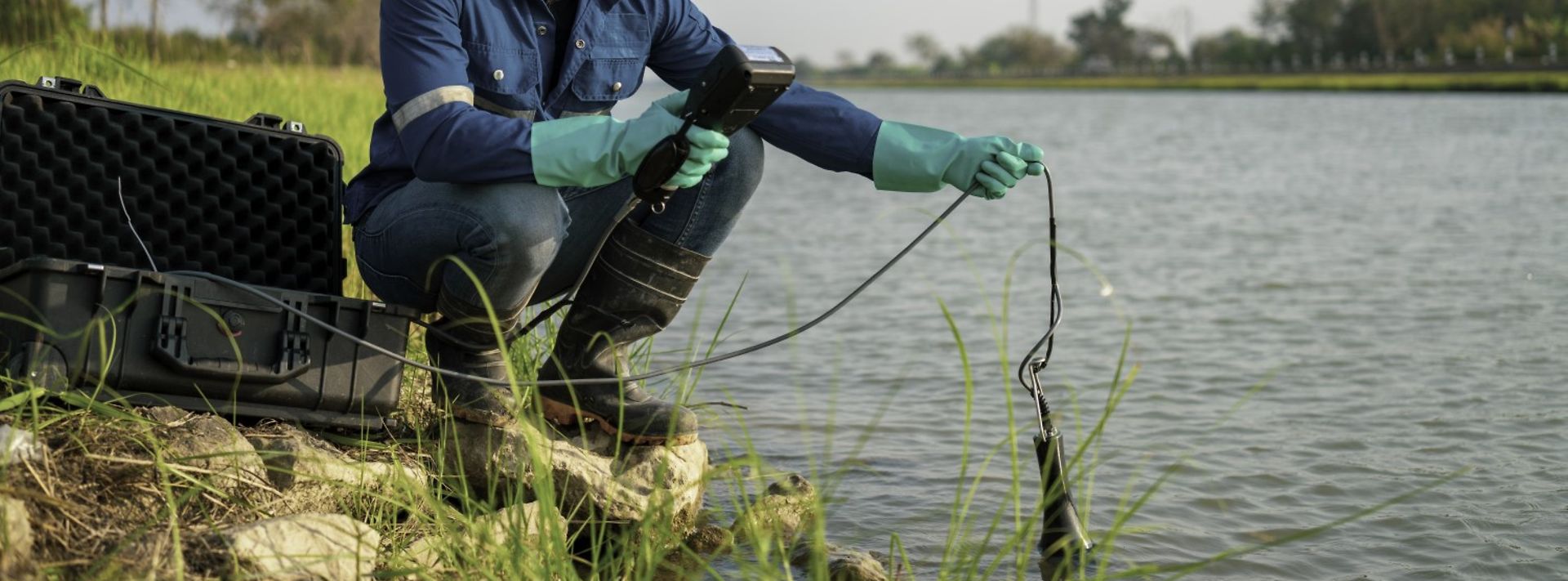 © istock.com/Chatchawal Ein Arbeiter nimmt eine Messung am Flussufer vor.