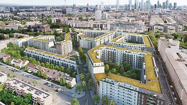 Eine Wohnanlage mit begrünten Dächern, umgeben von Bäumen, im Hintergrund eine Stadtlandschaft.