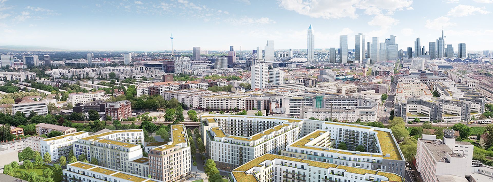 Eine Wohnanlage mit begrünten Dächern, umgeben von Bäumen, im Hintergrund eine Stadtlandschaft.