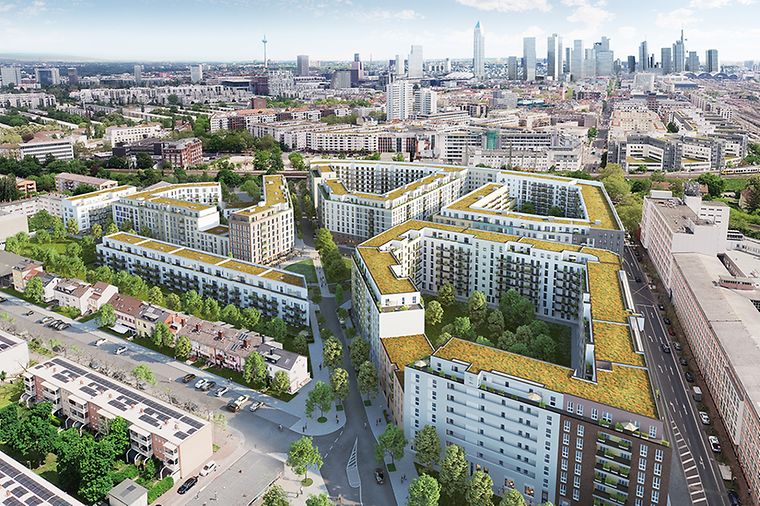 Eine Wohnanlage mit begrünten Dächern, umgeben von Bäumen, im Hintergrund eine Stadtlandschaft.