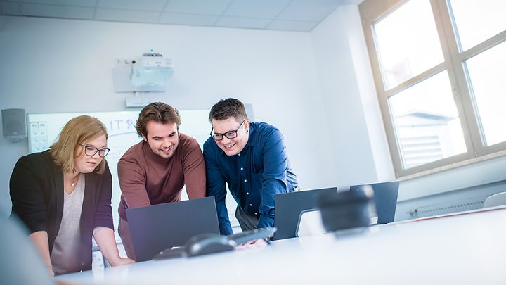 © Mainova Drei Studierende lehnen sich über Notebook und schauen auf den Monitor
