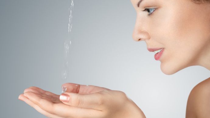 © www.istockphoto.com/Avesun Frau im Profil fängt Wasserstrahl mit den Händen auf