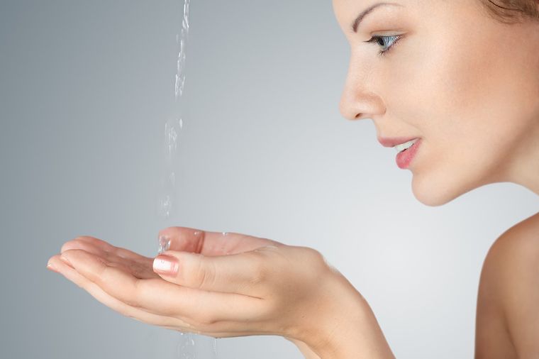 © www.istockphoto.com/Avesun Frau im Profil fängt Wasserstrahl mit den Händen auf