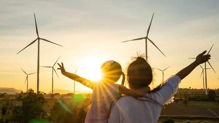 Mutter mit Tochter im Abendrot vor Windrädern