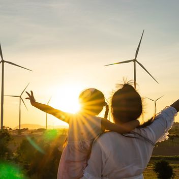 © www.istock.com/undefined undefined Mutter mit Tochter im Abendrot vor Windrädern