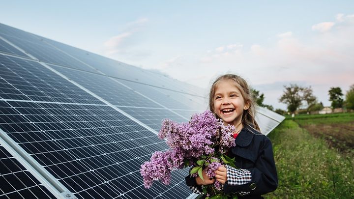 Kind mit Feldblumen an einer PV-Anlage