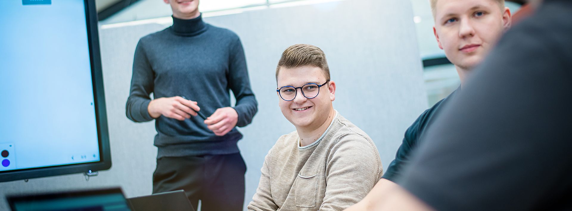 Junge Auszubildende sitzen zusammen und hören einen Auszubildenden zu