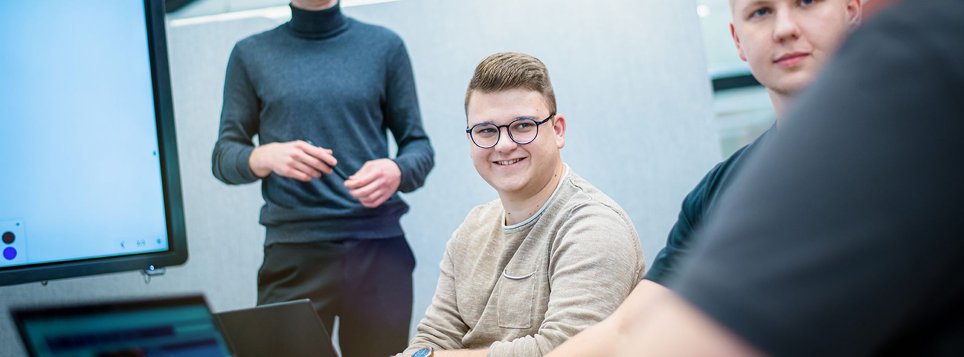 Junge Auszubildende sitzen zusammen und hören einen Auszubildenden zu