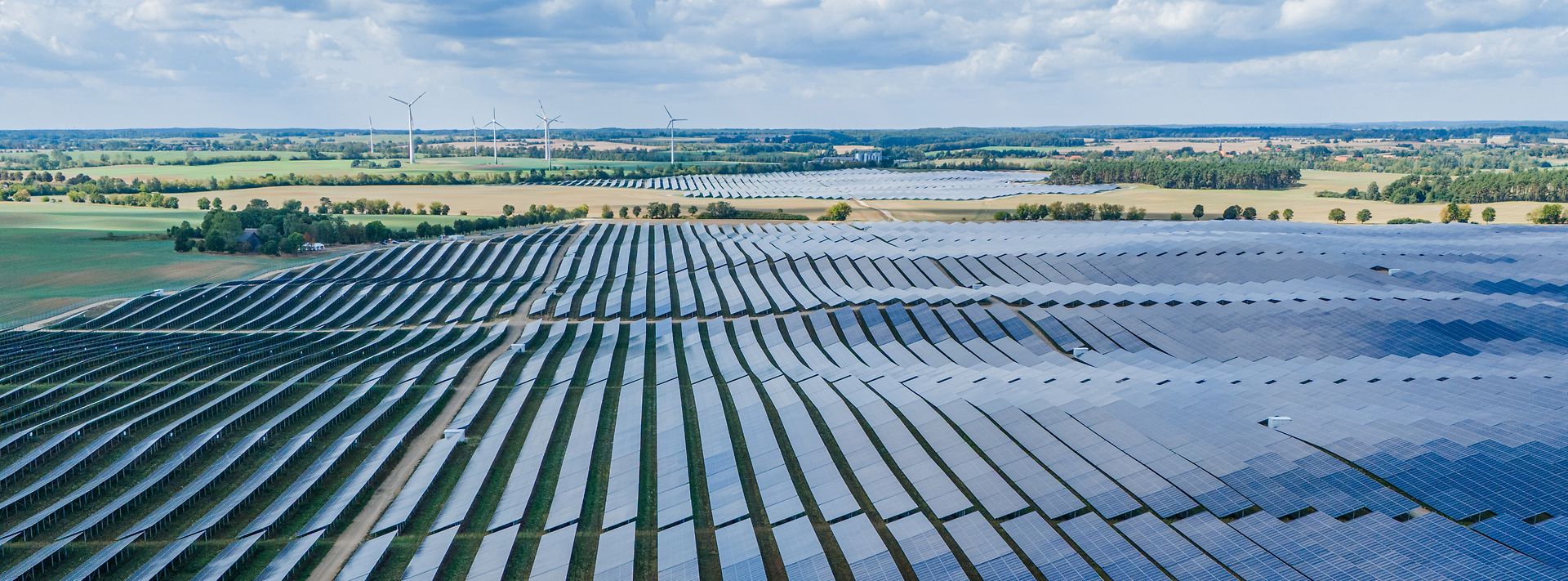 © Mainova Endlose Solarpanels, Windräder am Horizont, unter blauem Himmel.