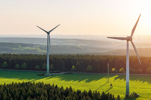 Luftaufnahme von Windrädern und der untergehenden Sonne.