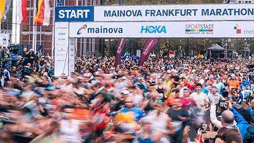 Start des Frankfurt Marathons mit Läufermenge und Zuschauern unter Werbebannern.