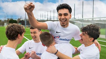 Siegfeiernde Sportmannschaft in Trikots, eine Person hebt die Faust.