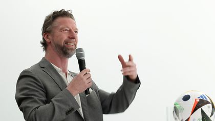Eine Person spricht am Mikrofone und gestikuliert 
