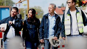 © Mainova Vier Personen in Arbeitskleidung und Sicherheitsausrüstung stehen auf einer Baustelle und schauen in die Ferne.